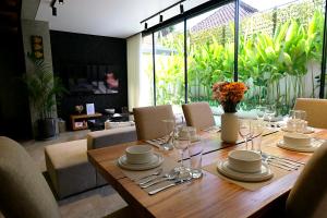 a wooden table with plates and wine glasses on it at SWOI LOFT UMALAs Designer 2BR Private Pool Villa in Kerobokan