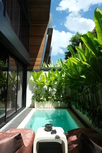 a swimming pool next to a house with plants at SWOI LOFT UMALAs Designer 2BR Private Pool Villa in Kerobokan