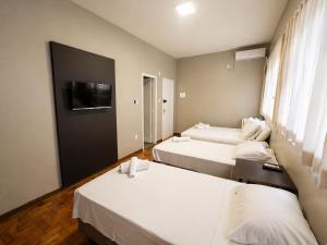 a hotel room with two beds and a flat screen tv at Hotel Divinopolis Center in Divinópolis