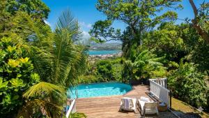 a pool on a wooden deck with a view of the ocean at L'Ombre de L'Eucalyptus Bel Appart Chambre-Salon Vue Mer & Piscine in La Trinité