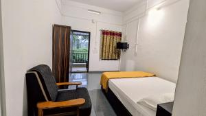 a room with a bed and a chair and a window at Winter Bloom Homestay Munnar in Munnar