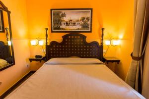 1 dormitorio con 1 cama con 2 lámparas y 1 pintura en Hotel dei Coloniali, en Siracusa