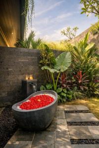 a bath tub filled with red flowers in a garden at The Garden Villas in Ubud