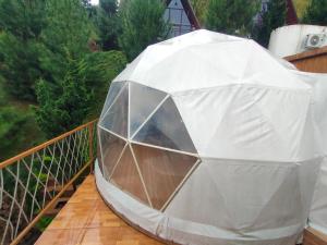 a tent on a balcony with trees in the background at Glamping Dome Kusumanagara 2 in Bandung