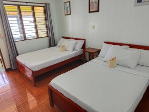 two beds in a room with two windows at Hadefe Cottages Beach Front in El Nido