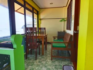 a dining room with a table and chairs and windows at Hadefe Cottages Beach Front in El Nido