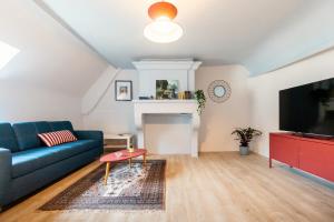 a living room with a blue couch and a tv at Le Bleu et Rubis in Falaise