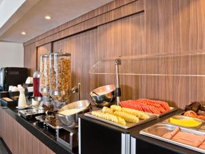 a buffet line with food on a counter in a restaurant at City Express by Marriott Santiago Aeropuerto in Santiago