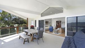 a living room with a table and chairs on a balcony at For - Resters in Wamberal