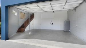 an empty garage with a staircase and a refrigerator at For - Resters in Wamberal