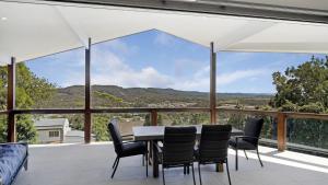 a dining room with a table and chairs on a balcony at For - Resters in Wamberal