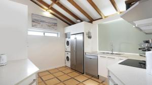 a kitchen with a stainless steel refrigerator and white cabinets at For - Resters in Wamberal +16 photos