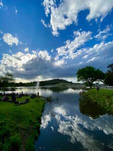 a river with people sitting on the grass next to it at Refugio Viggena in Tandil