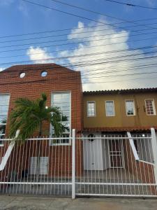 a red brick house with a white fence at Casa Vacacional in Tucacas