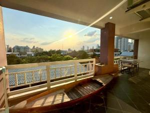 a bench on a balcony with a view of the city at Baan Sabai Rama IV Apartment in Bangkok