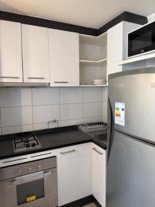 a kitchen with white cabinets and a stainless steel refrigerator at 2108 Depto a 15 minutos del Aeropuerto frente mall in Santiago