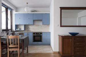 a kitchen with blue cabinets and a table with chairs at Apartament BB in Krynica Zdrój