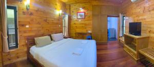 a bedroom with a white bed and a television at Baan Soontree Resort in Chiang Rai