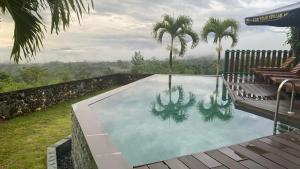 a swimming pool with palm trees in a backyard at Balibo Fort Hotel in Balibo