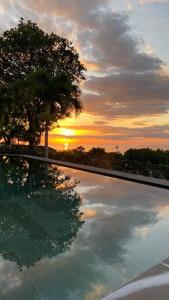 a reflection of a sunset in a pool with a tree at Balibo Fort Hotel in Balibo +14 photos