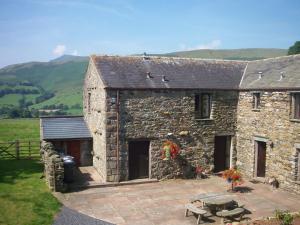 a stone building with a patio in front of it at Saddleback Barn in Penrith