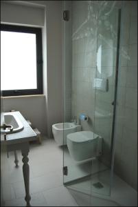a bathroom with a toilet and a glass shower at Hotel Acquamarina in Donnalucata