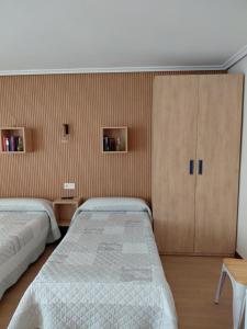 a bedroom with two beds and a cabinet at Pensión Amaia in Vitoria-Gasteiz