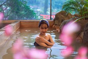 a woman is sitting in a pool of water at The Onsen Hot Spring Resort in Batu