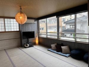 a living room with a tv and two windows at SakuraPiso in Kagoshima