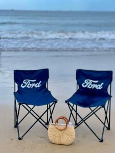two blue chairs sitting on the beach with a purse at Ánh Dương Local Mini Tour in An Lợi (4)