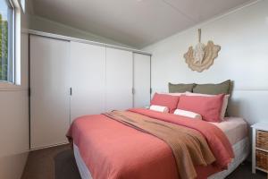 a bedroom with a large bed with pink pillows at Ngongotahā Getaway in Rotorua