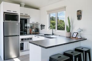 a kitchen with white cabinets and a stainless steel refrigerator at Ngongotahā Getaway in Rotorua