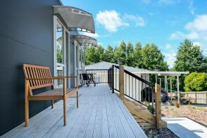 a wooden deck with a bench on a house at Ngongotahā Getaway in Rotorua +3 photos