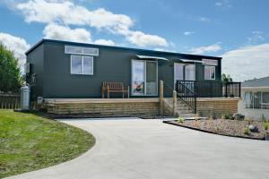 a small green house with a chair on a driveway at Ngongotahā Getaway in Rotorua