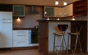 kuchnia z białymi szafkami i stołkami barowymi w obiekcie Apartament Sonata w mieście Krynica Zdrój