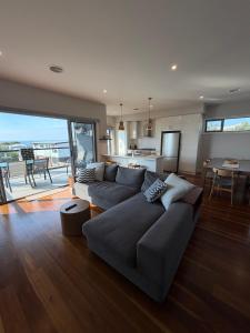 a living room with a large couch and a kitchen at Oceans 15- Stunning Home Ocean Views close to Wineries Restaurants and Golf Course in Portarlington