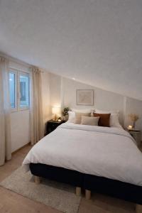 a bedroom with a large white bed and a window at Trianon Location in Bagnols-en-Forêt
