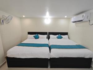 two beds in a small room with white walls and blue pillows at HOTEL VAJRA Grand in Tirupati