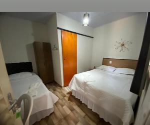 a bedroom with two beds and a clock on the wall at Belo Hotel in Ribas do Rio Pardo