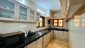 a kitchen with white cabinets and a black counter top at Odrine's abode - Udupi in Kalyānpur