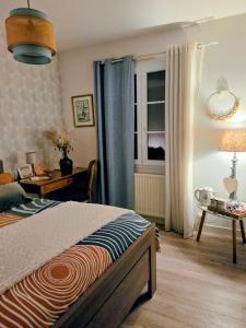 a bedroom with a bed and a table and a window at chambre d'hôte chez Mimidid in Le Landreau +17 photos