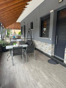 a patio with a table and chairs in front of a house at Grey Pearls Apartments in Nea Vrasna