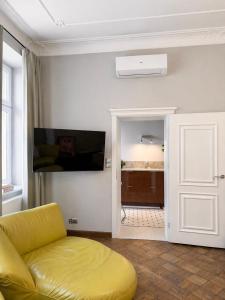 a living room with a yellow couch and a flat screen tv at Maison Stefana Rynek in Rzeszów +28 photos