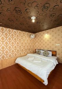 a bedroom with a bed with white sheets and a ceiling at Mughal resort pahalgam in Pahalgām