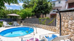 a swimming pool with chairs and a rock wall at Villa Risika 2 with pool island Krk by Villas Guid in Risika
