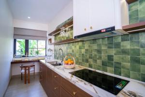 a kitchen with green tiles on the wall and a sink at AT Homestay Huế in Thôn Lại Thê