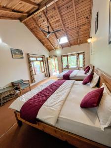 two large beds in a room with wooden ceilings at Oak Essence in Mukteshwar