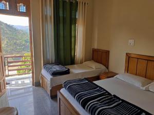 a room with two beds and a window with a view at Vijay Residency in Barkot +39 photos