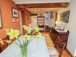a dining room with a table with yellow flowers in a vase at Two Town End in Penrith