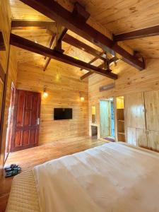 a bedroom with a large bed in a wooden room at Homestay Gió Mộc !! in Làng Môn